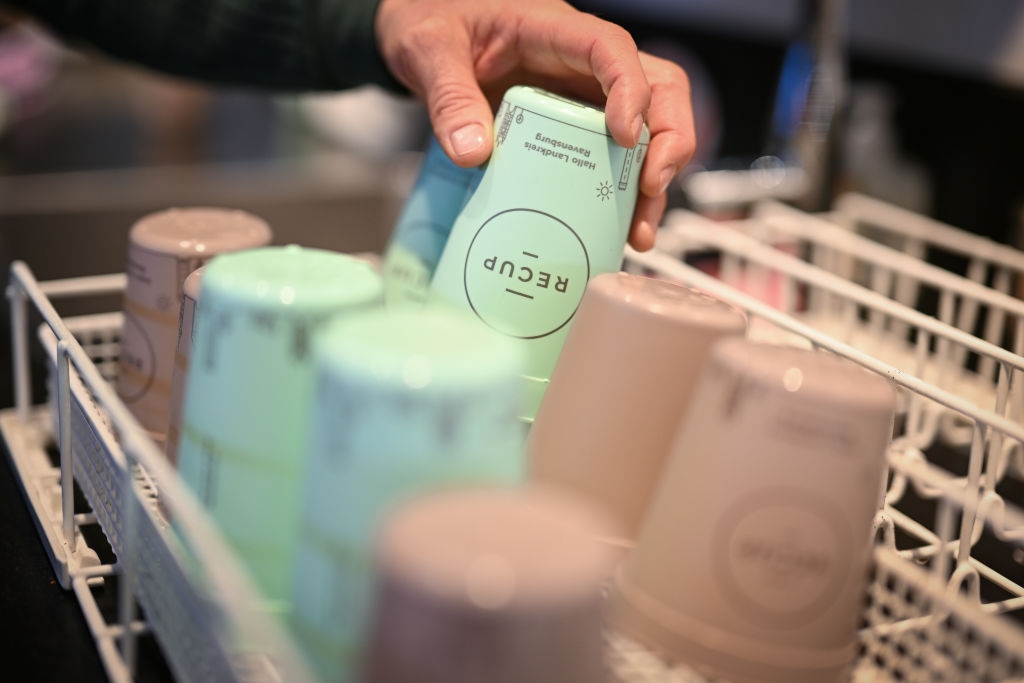 Reusable cups being placed into a dishwasher rack, promoting sustainable practices