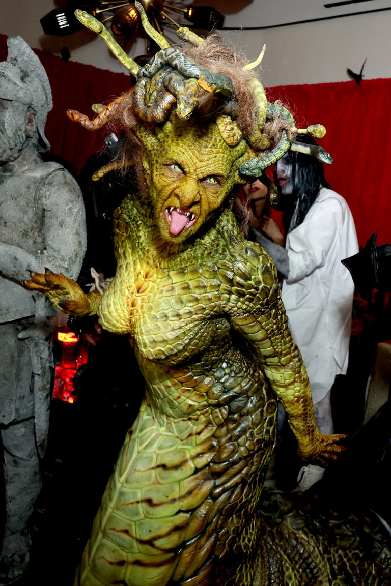 Heidi Klum in a Medusa costume with green scales, snakes for hair, fangs, and a tongue sticking out.