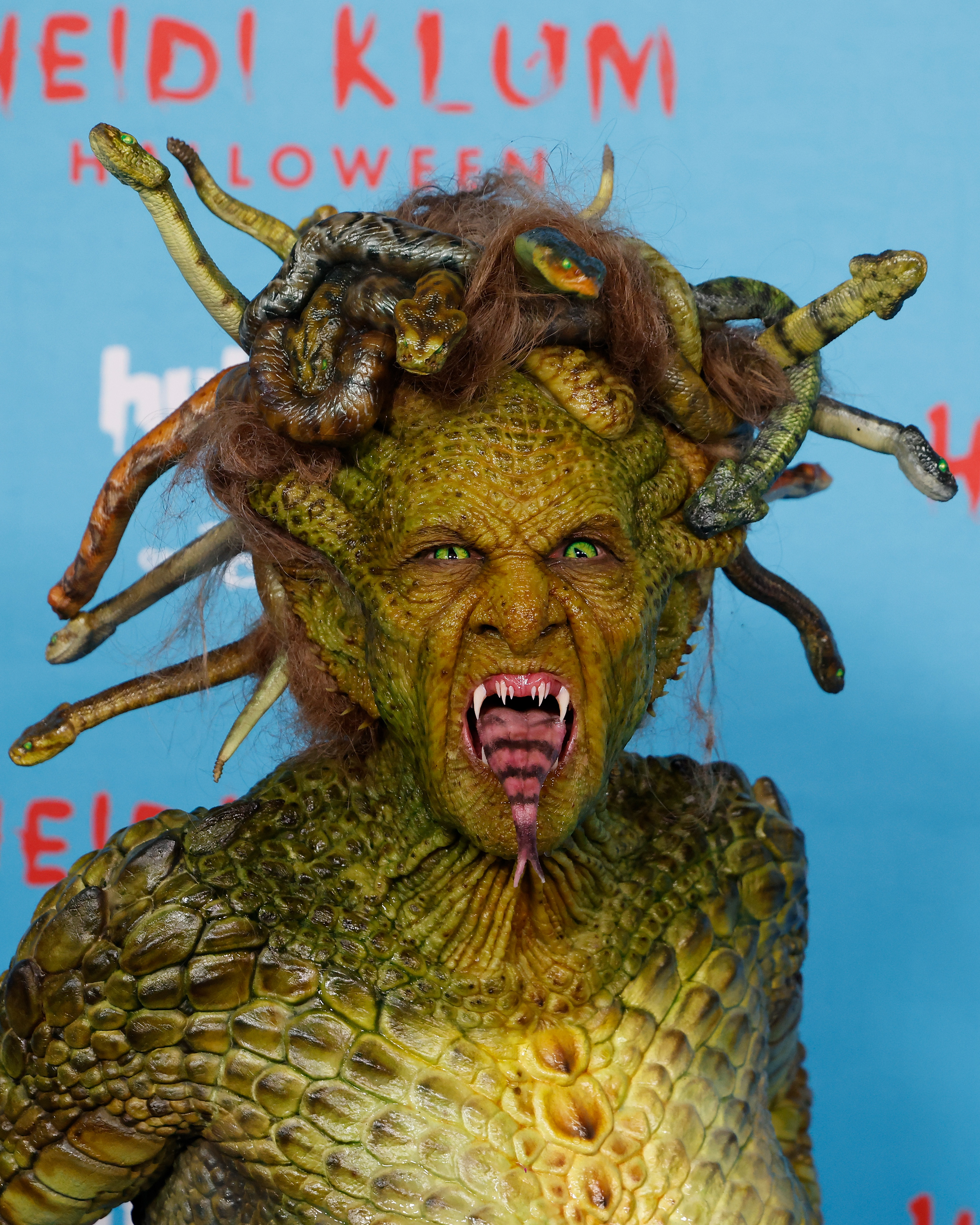 Heidi Klum dressed as Medusa for Halloween, with green snake-eyes, fangs, and snakes for hair.