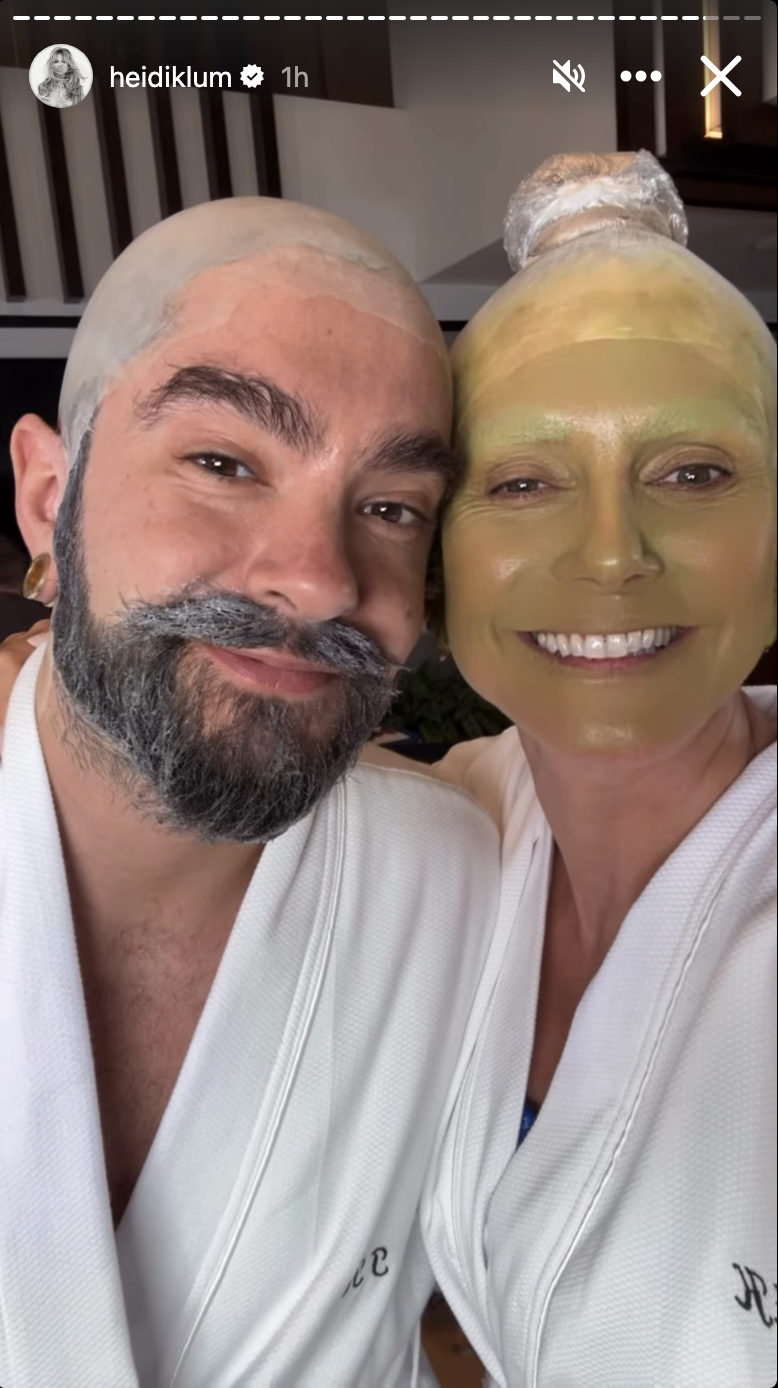 Heidi Klum and Tom Kaulitz wearing bald caps, robes, and makeup, with Klum's face painted yellow-green.