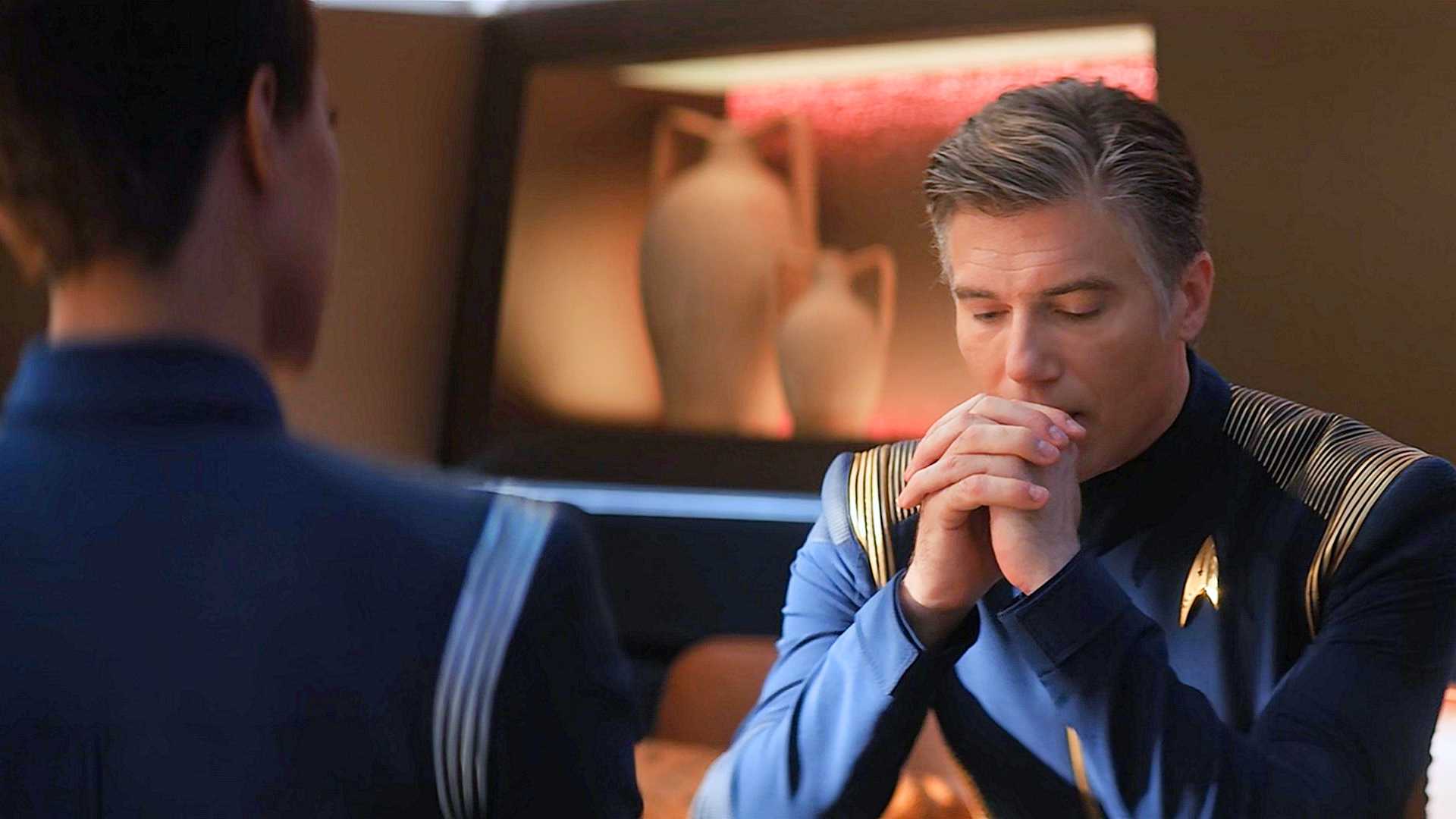 Michael Burnham, back to camera, facing Captain Pike, looking down hands clasped by his mouth, in the ready room from Star Trek Discovery