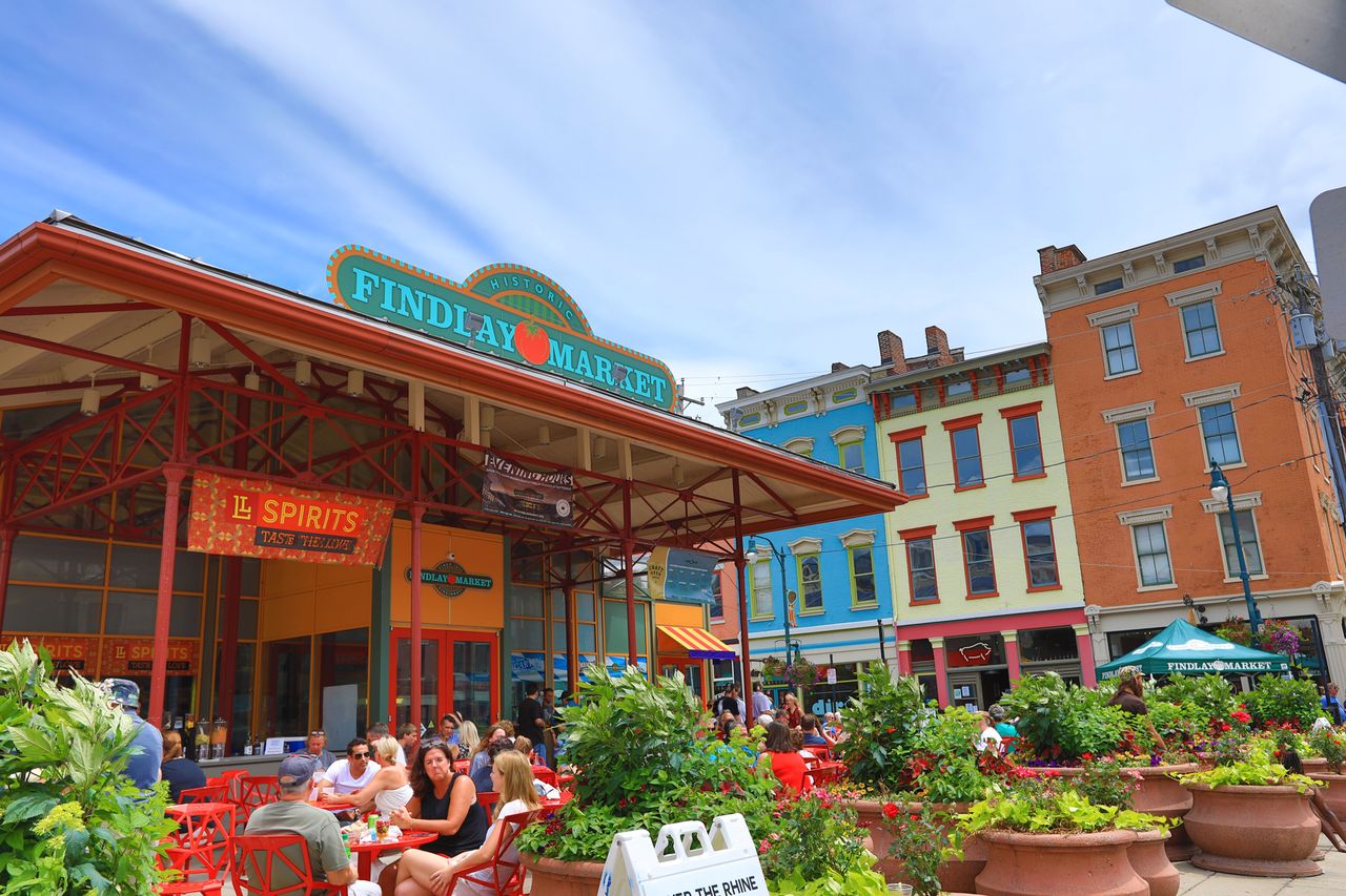 A view of Findlay Market in Cincinnati with customers seated at outdoor tables and colorful buildings in the background