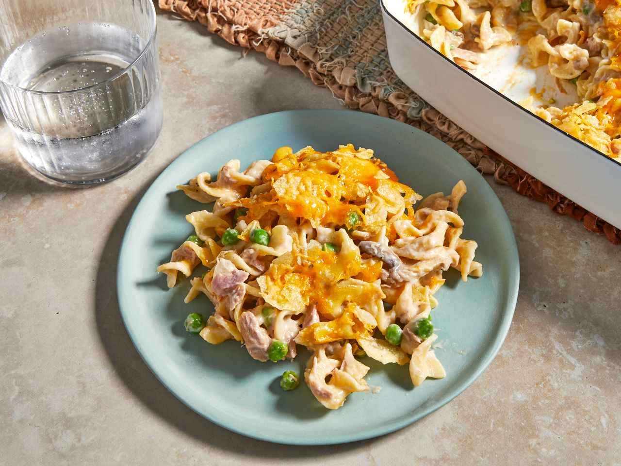 a high angle view of a plate of the best tuna noodle casserole with the casserole dish sitting nearby
