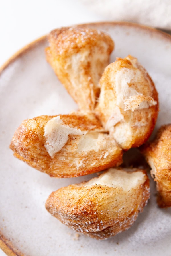 broken open cinnamon pull apart muffin on a white plate.