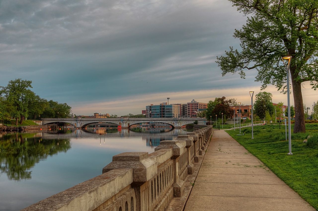 A pleasing ccenic view along the East Bank Trail in South Bend, Indiana. A view of the Jefferson Blvd bridge with its arched supports reflected in the smooth surface of the St. Joesph River.