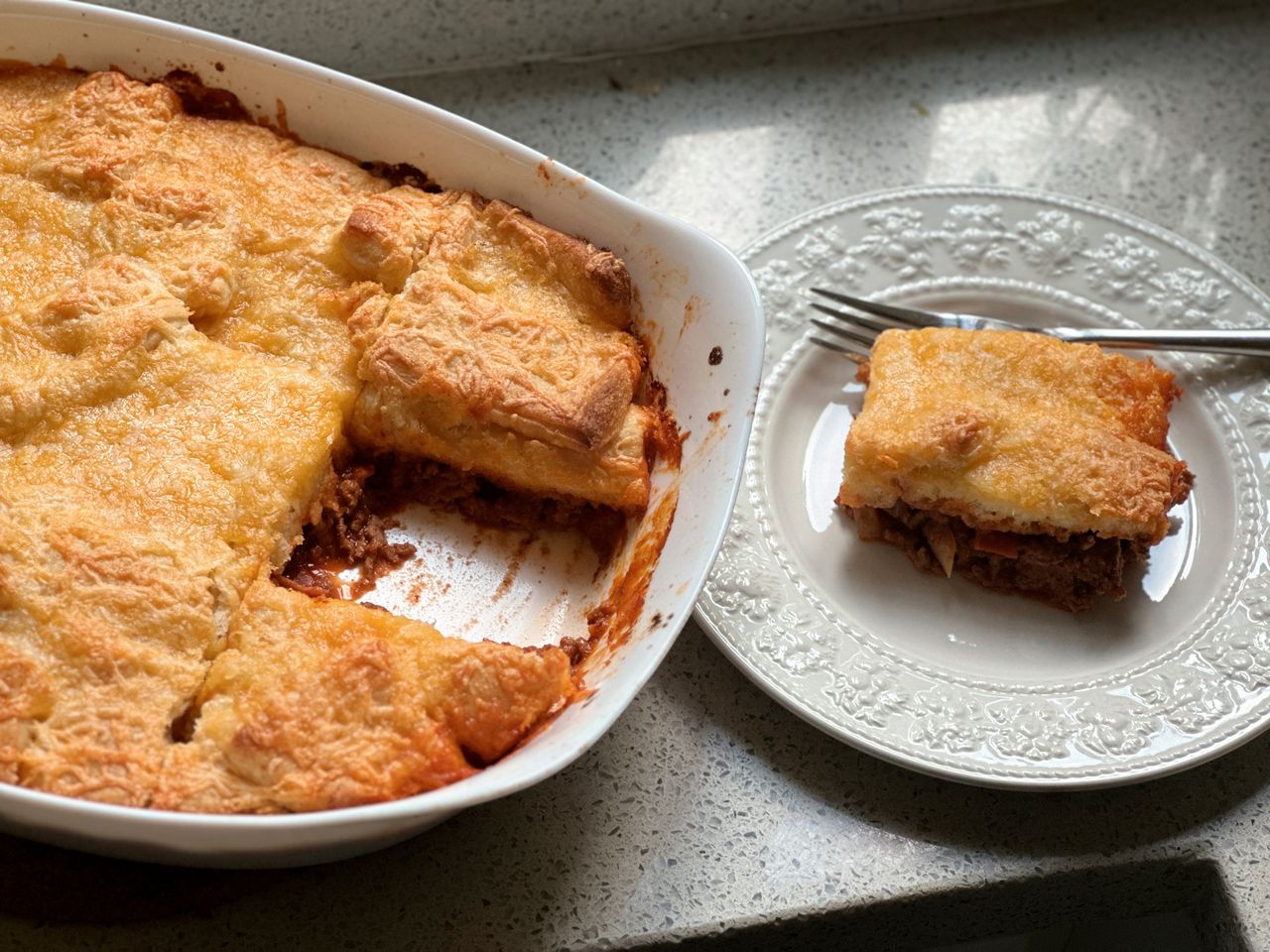 pan of Pizza Breadstick casserole with a piece on a plate