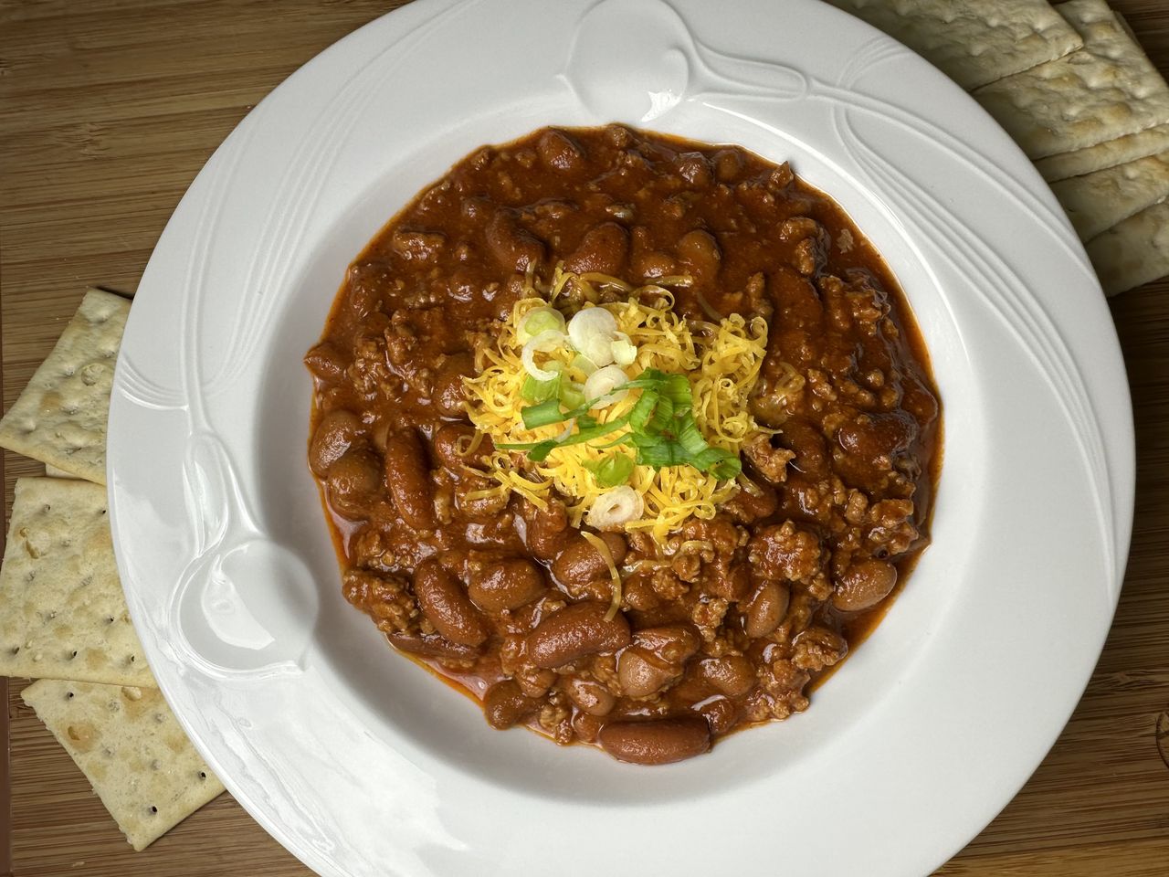 thick bean chili with cheese and green onion garnish