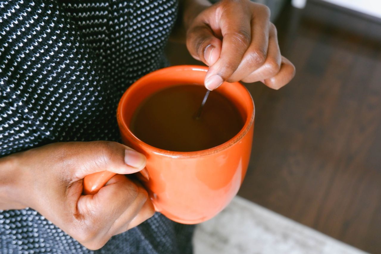 Stock, woman stirring cup of coffee