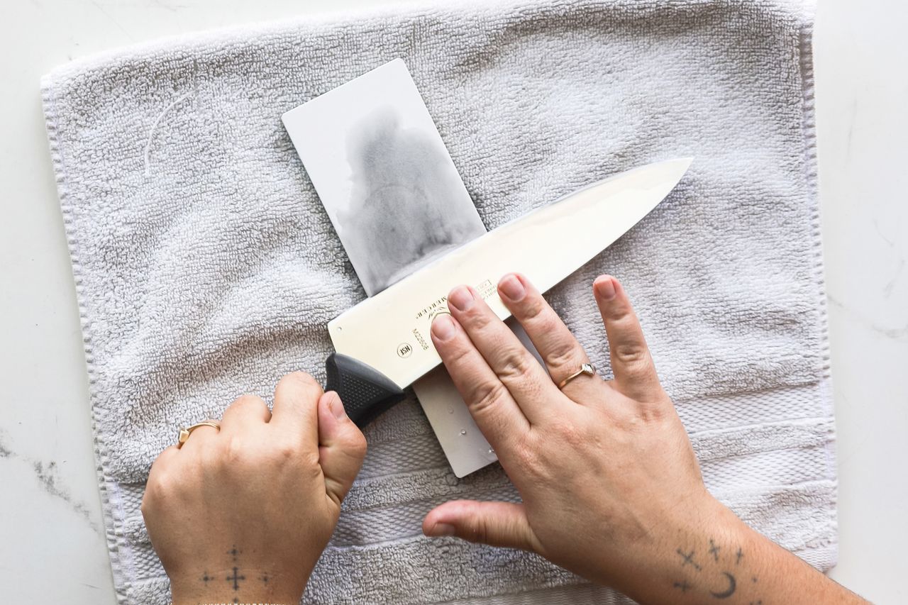 A person using a glass sharpening stone over a white towel