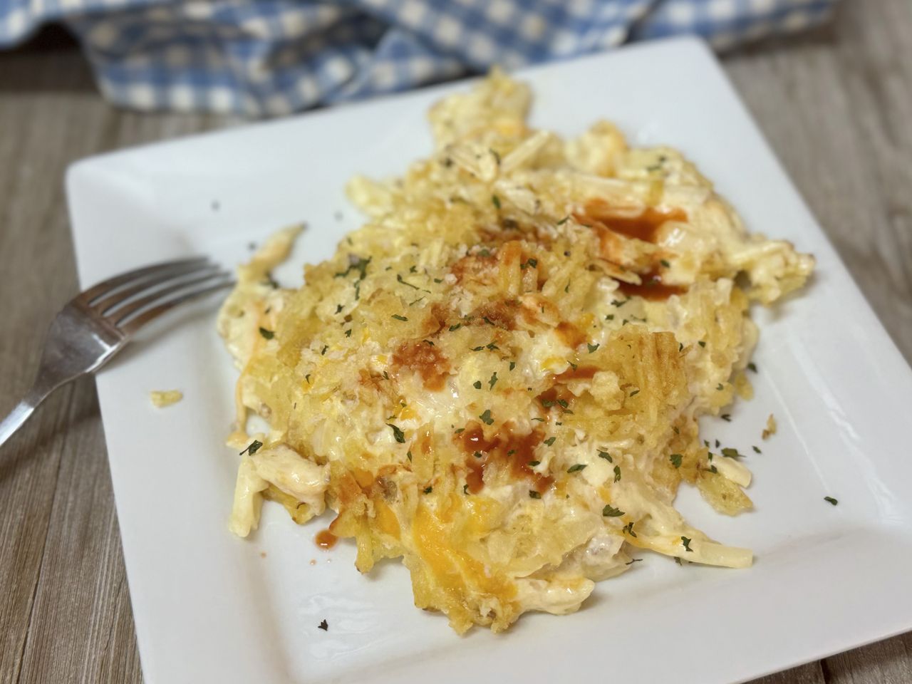 A close up of portion of hash brown casserole on a white plate