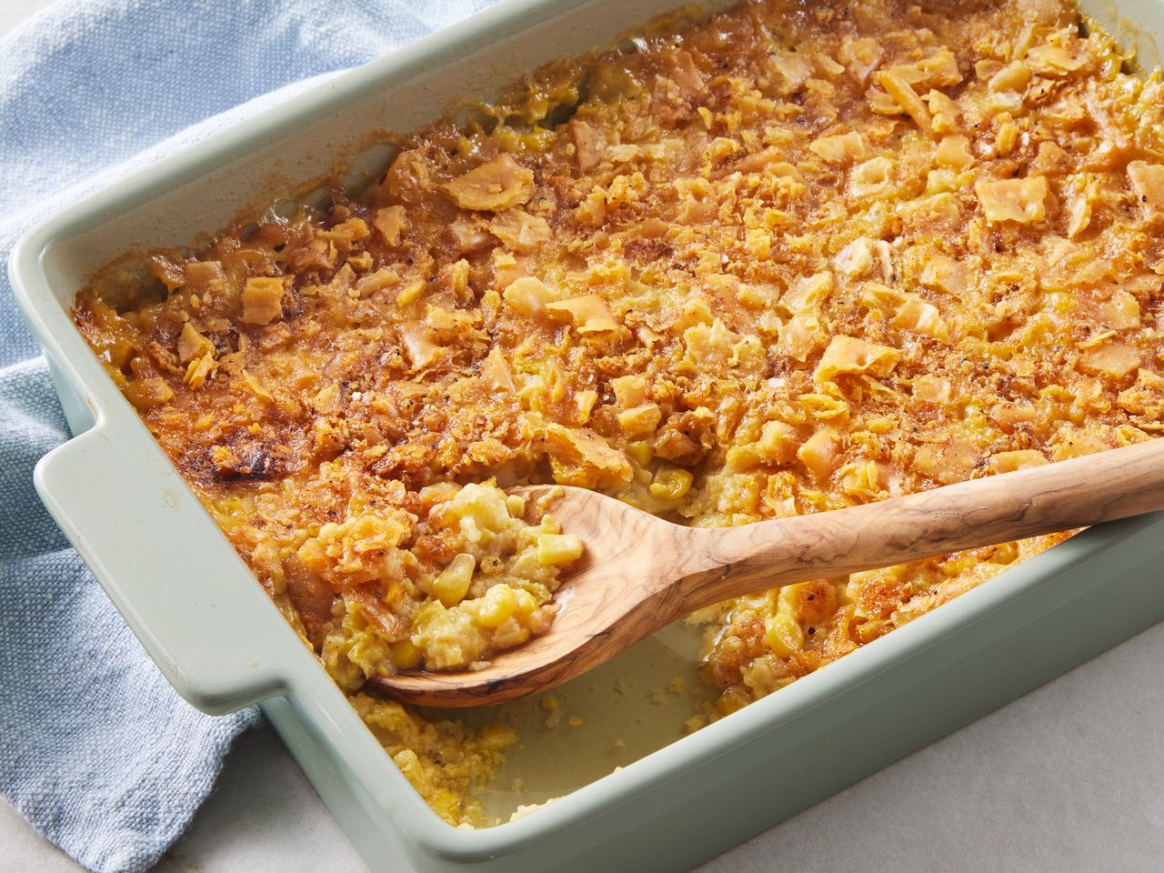 A baking dish of old fashioned scalloped corn with a serving spoon