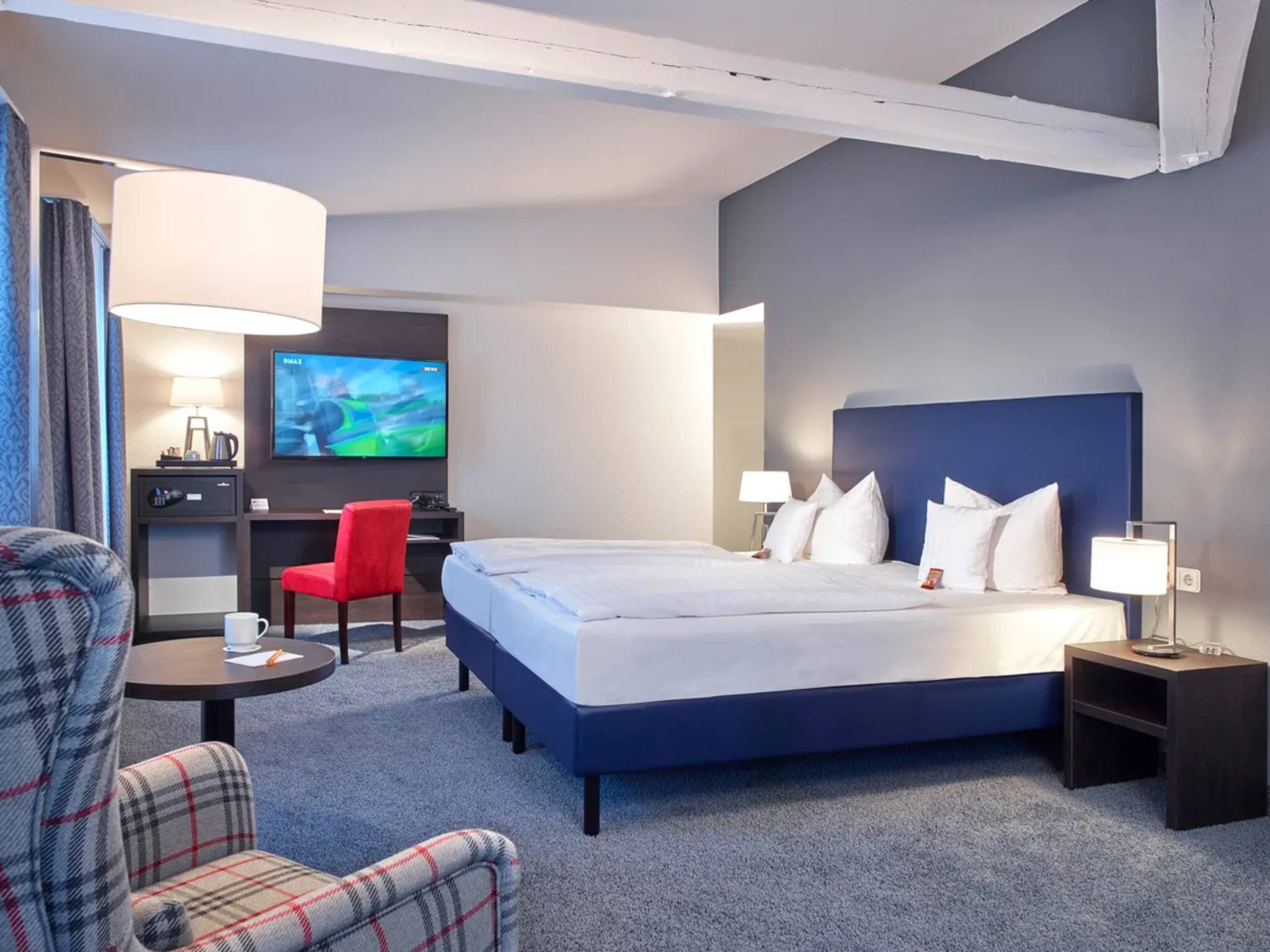 Komfortables Superior-Doppelzimmer mit gemütlicher Sitzecke, Kaffee- und Teestation sowie Flat-TV für entspannte Nächte. Quelle: tripz