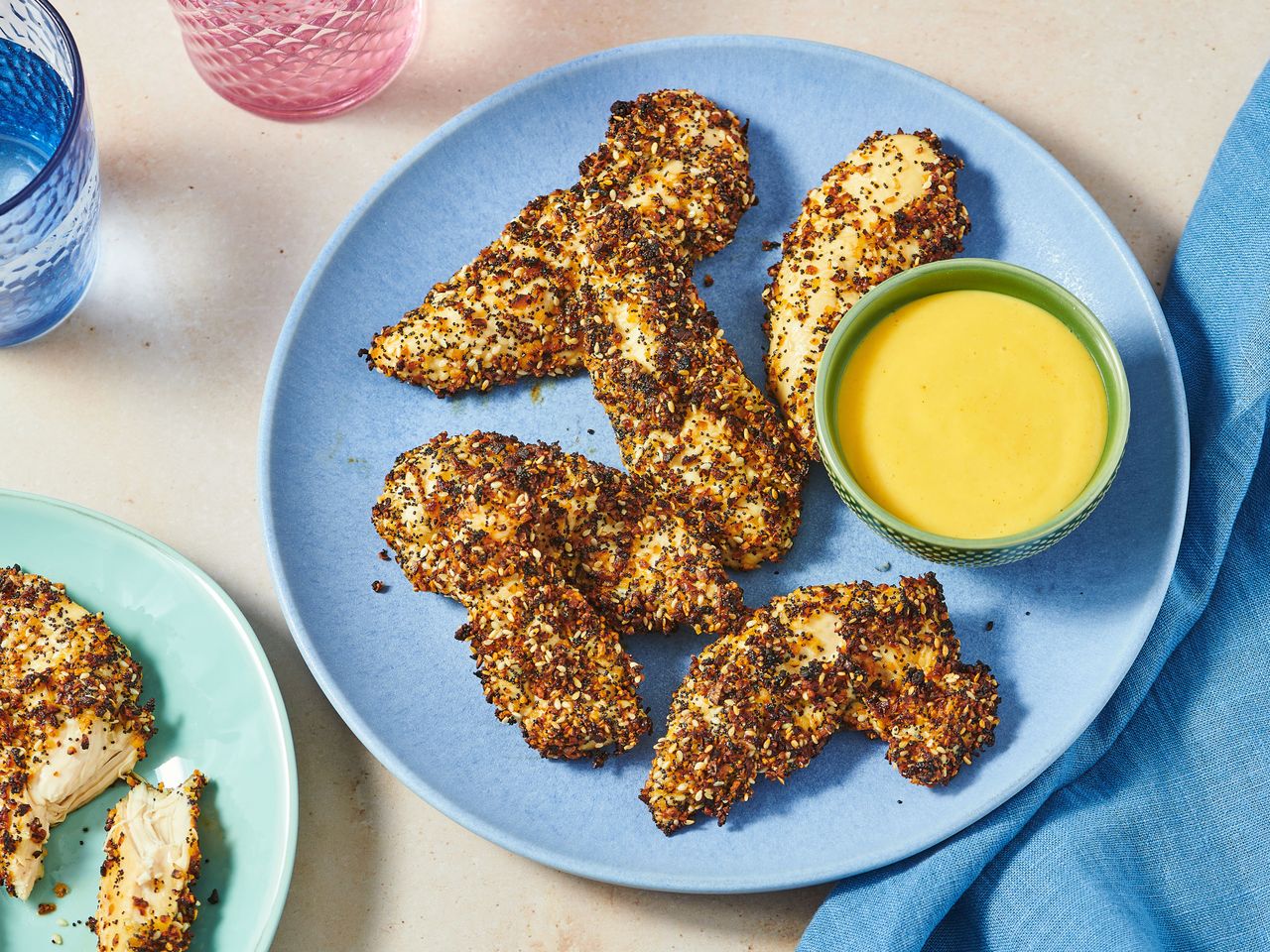Chicken strips with seasoning and a dipping sauce on plates