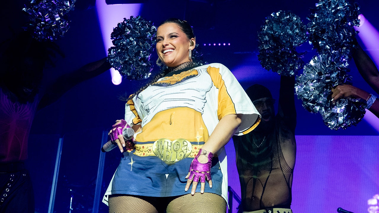 Nelly Furtado holds microphone on stage.