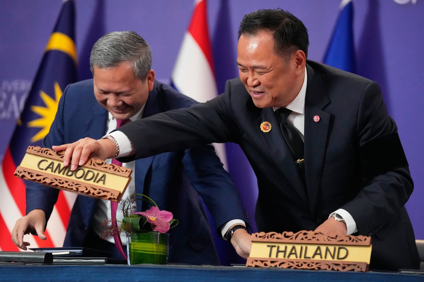 Cambodian Prime Minister Hun Manet, left and Thailand's Prime Minister Anutin Charnvirakul react as they switch country signs during a signing ceremony on the sidelines of the ASEAN Summit in Kuala Lumpur, Malaysia, Sunday, Oct. 26, 2025. (AP Photo/Mark Schiefelbein)