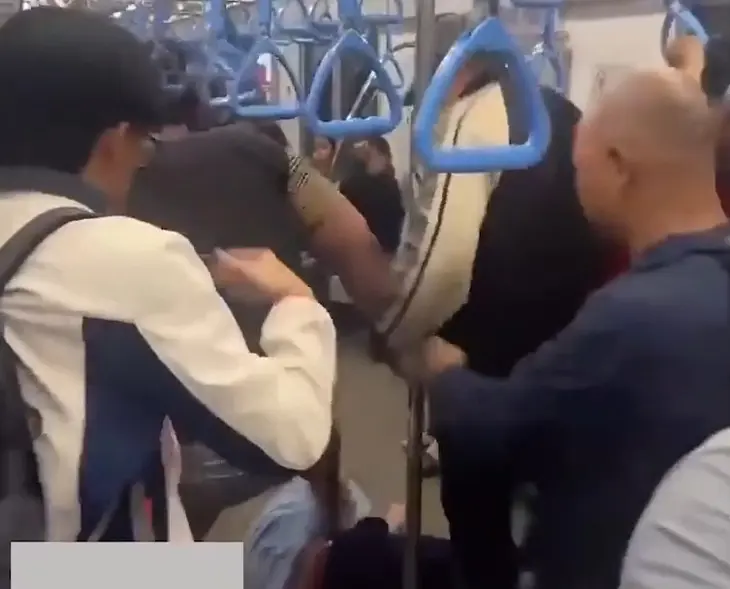 Nam bảo vệ bị hai nam thanh niên đánh nằm xuống nền toa tàu - Ảnh cắt từ clip do người dân quay lại