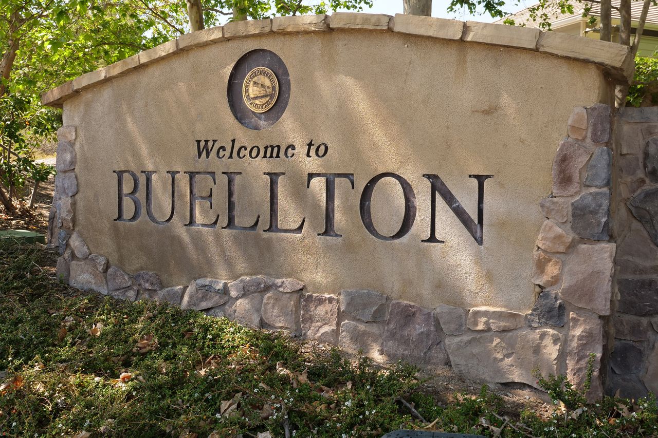 A stone sign with the text Welcome to Buellton and a circular emblem at the top surrounded by greenery and stonework