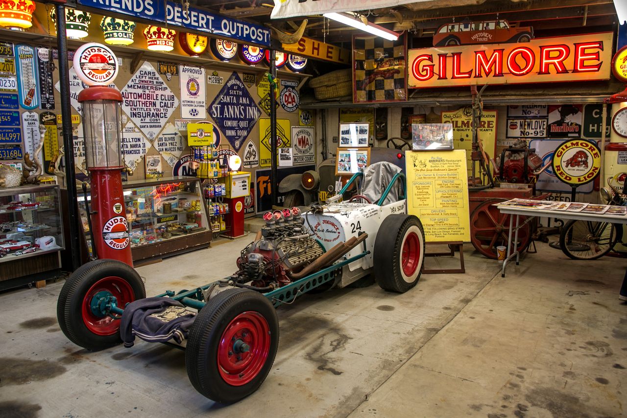 Vintage gas stationthemed museum featuring an antique race car various retro signs and memorabilia displayed around the space