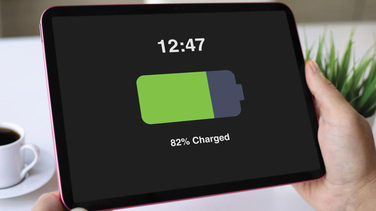 Person holding tablet with charged battery on the screen