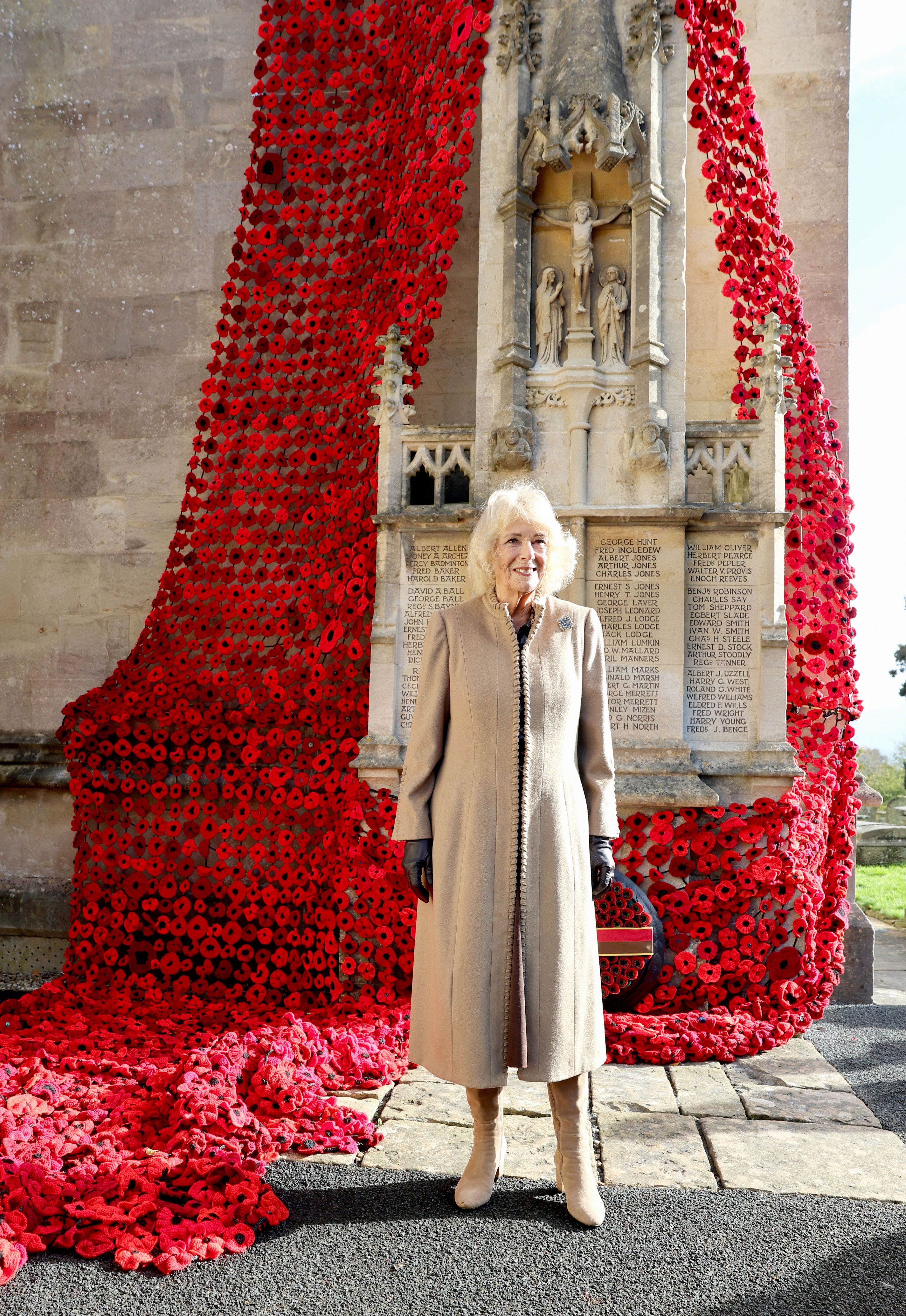 Queen Camilla jokes with volunteers as she visits huge war memorial display