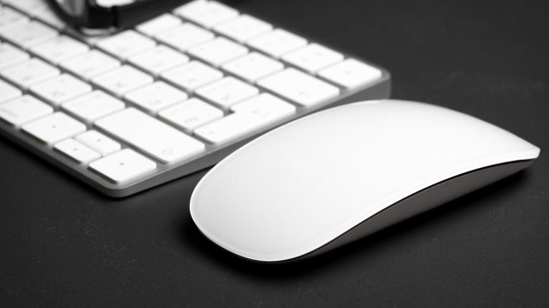 Closeup of Apple keyboard and mouse on black surface
