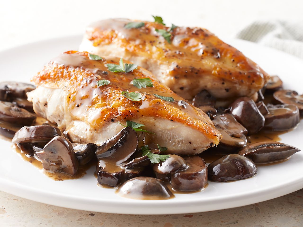 Cooked chicken breast served with mushrooms and sauce on a plate