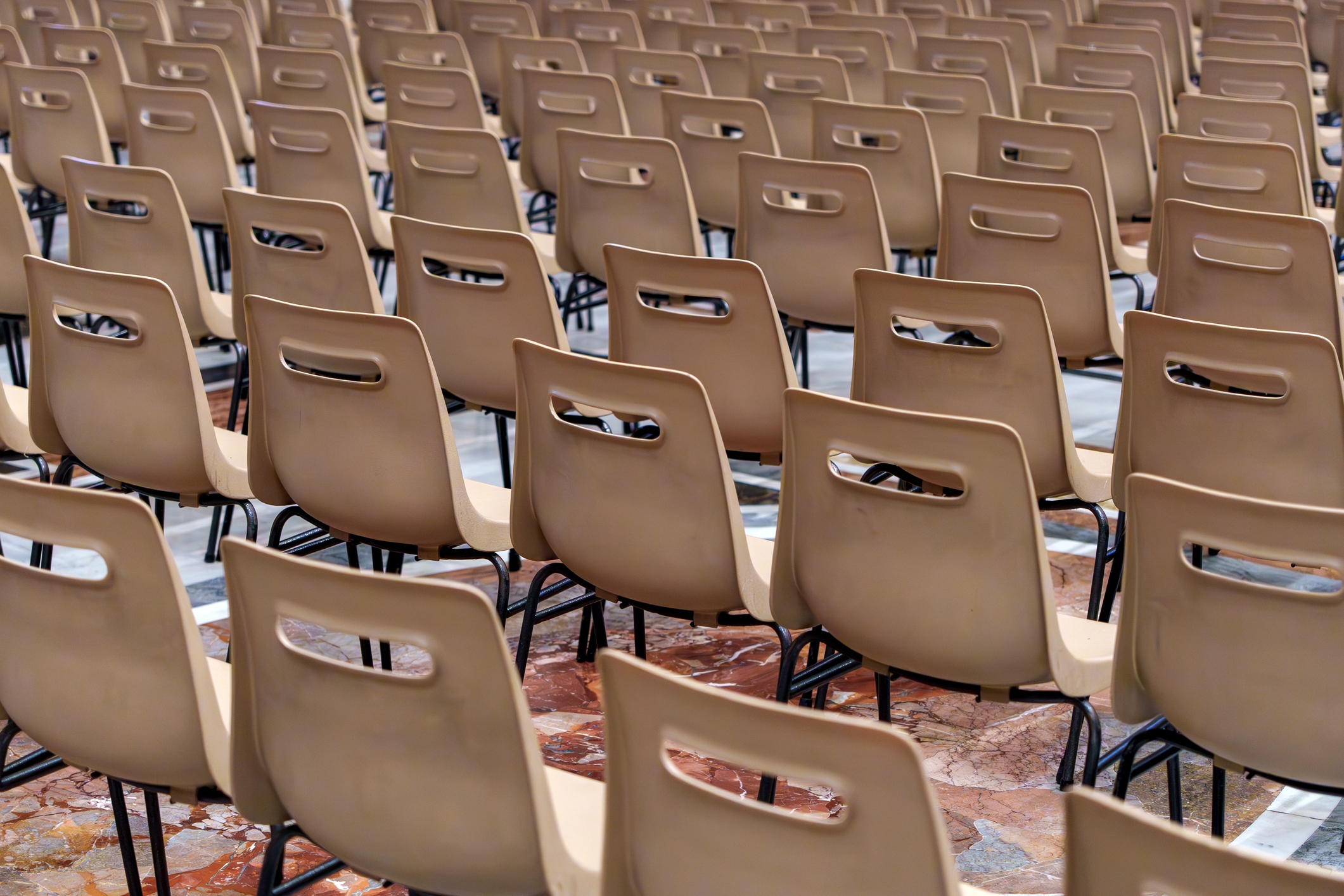 Rows of identical, empty chairs arranged closely together in an outdoor setting