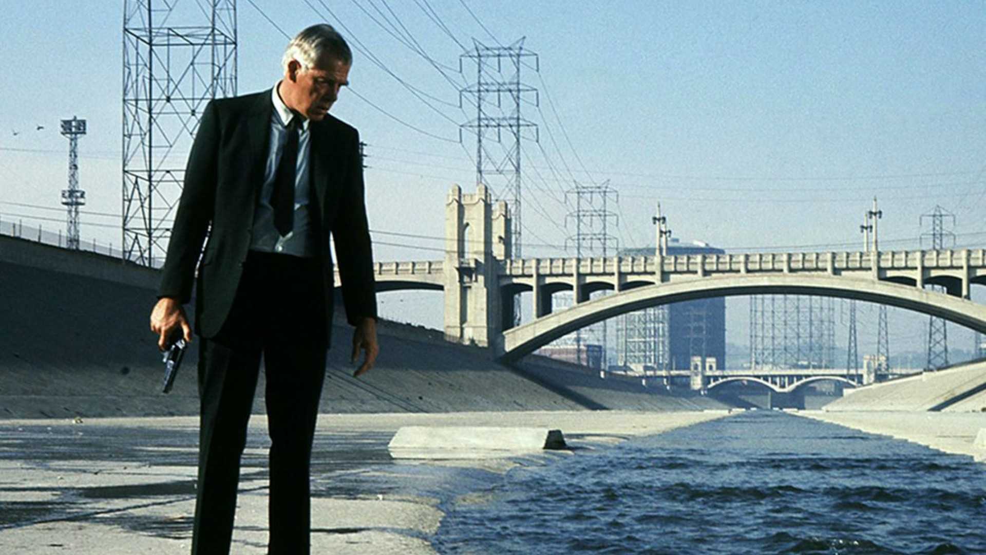 Lee Marvin looks dazed while looking down at something in the LA River in Point blank