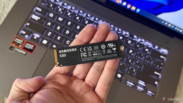 Holding an internal SSD in front of laptop.