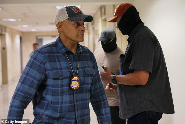 A federal immigration officer awaits migrants outside of a New York courtroom