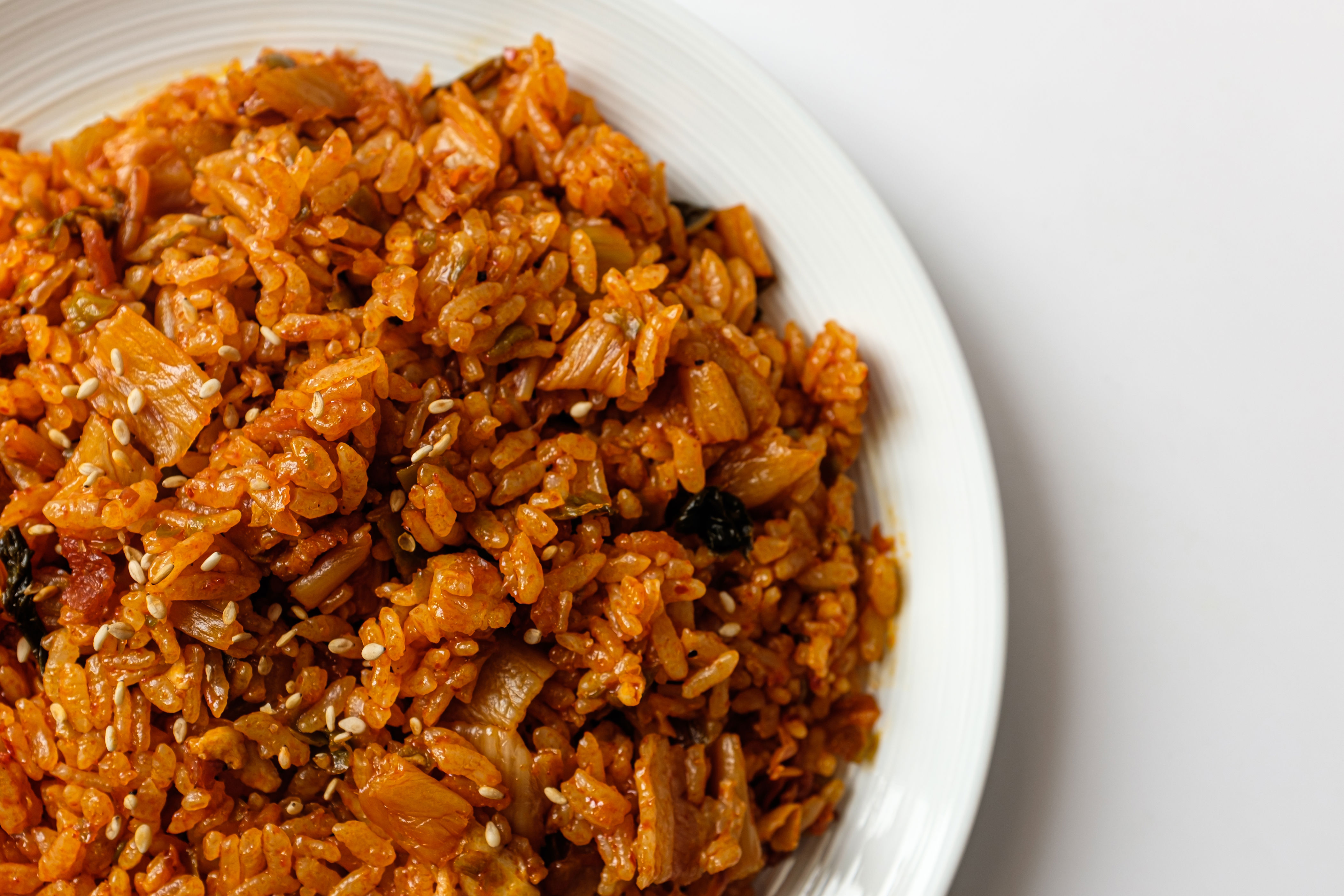 A close-up of a plate of seasoned rice with vegetables and sesame seeds, showcasing its texture and ingredients