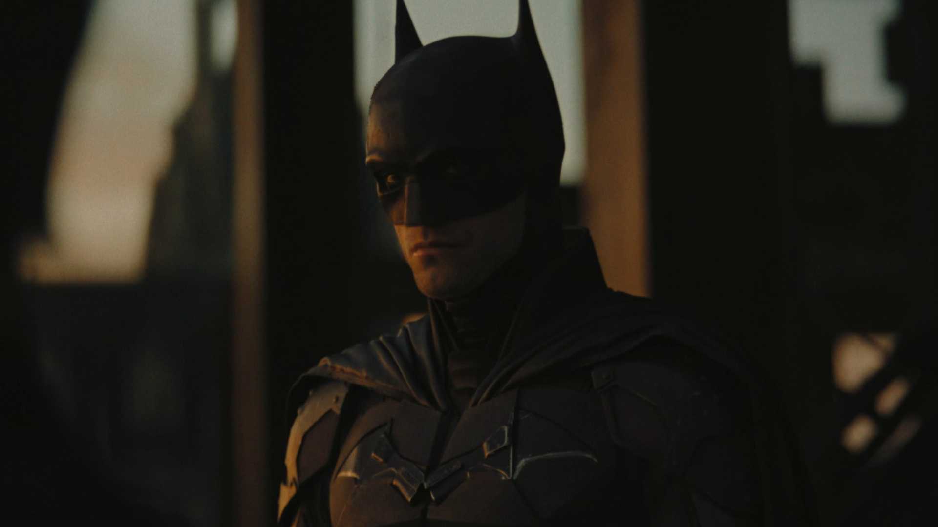 Robert Pattinson in costume as the sun rises behind him in The Batman