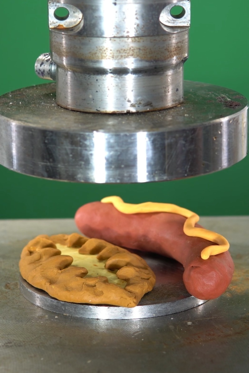 Hydraulic press crushing playdough food shapes