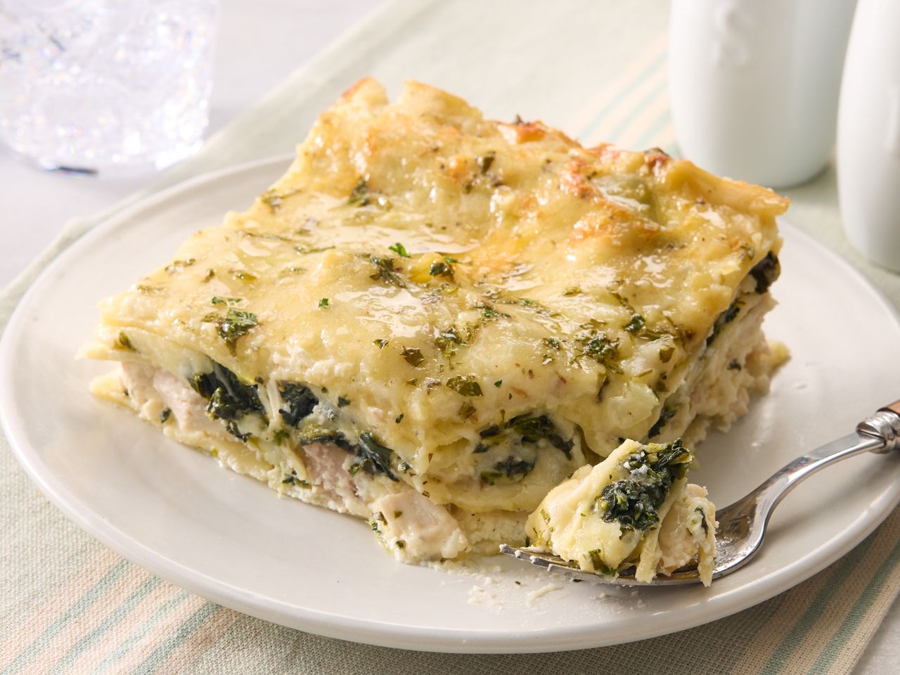 A serving of white chicken lasagna on a plate with a fork
