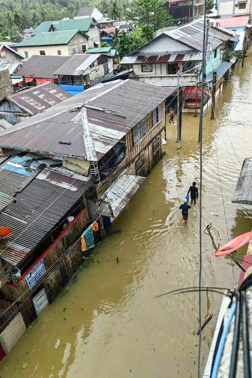 A photo taken by Mayor Benjie Ver shows people wading through a flooded street following heavy rains in Jipapad town, Eastern Samar province