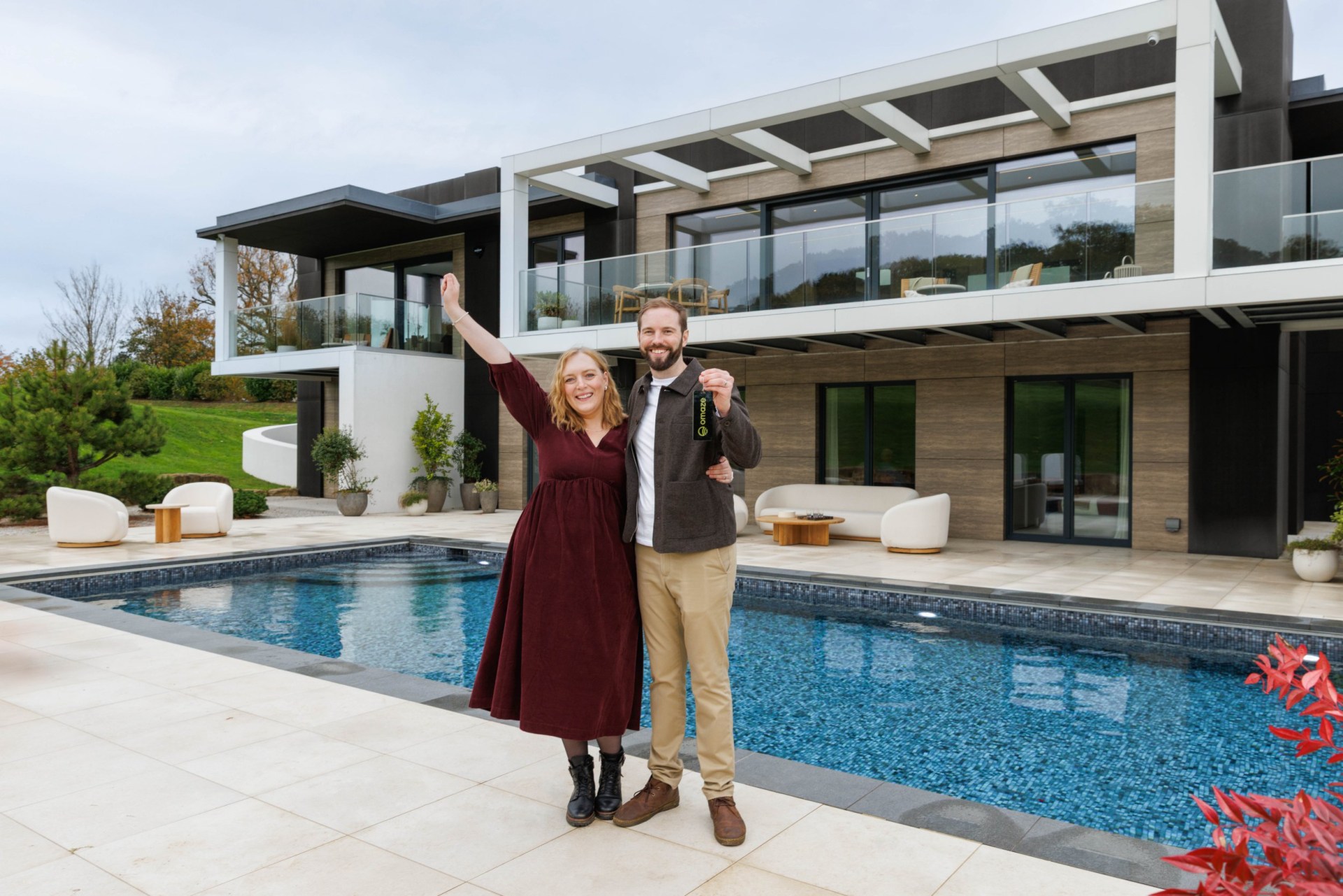 Alistair Walker and wife Naomi posing in front of the £4 million Surrey mansion they won through Omaze.