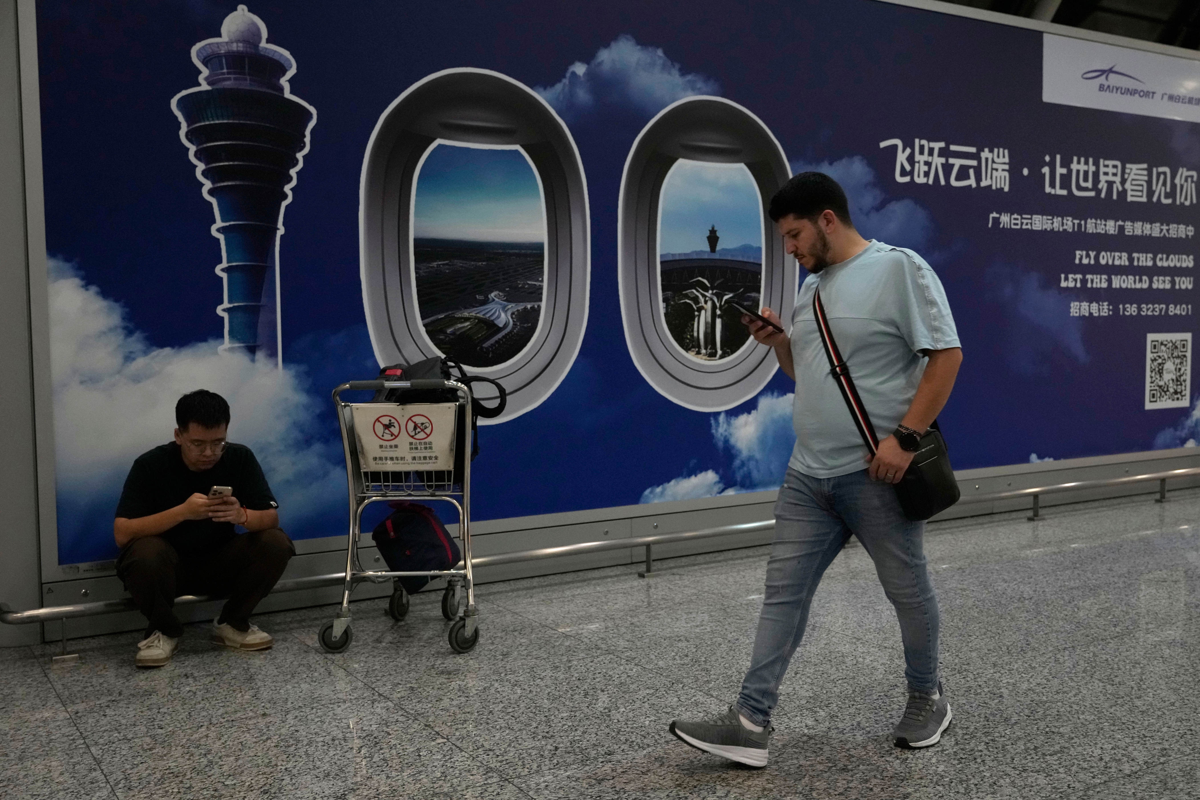 A person walks past a sign board for the Baiyun airport in Guangzhou in southern China's Guangdong province (AP)