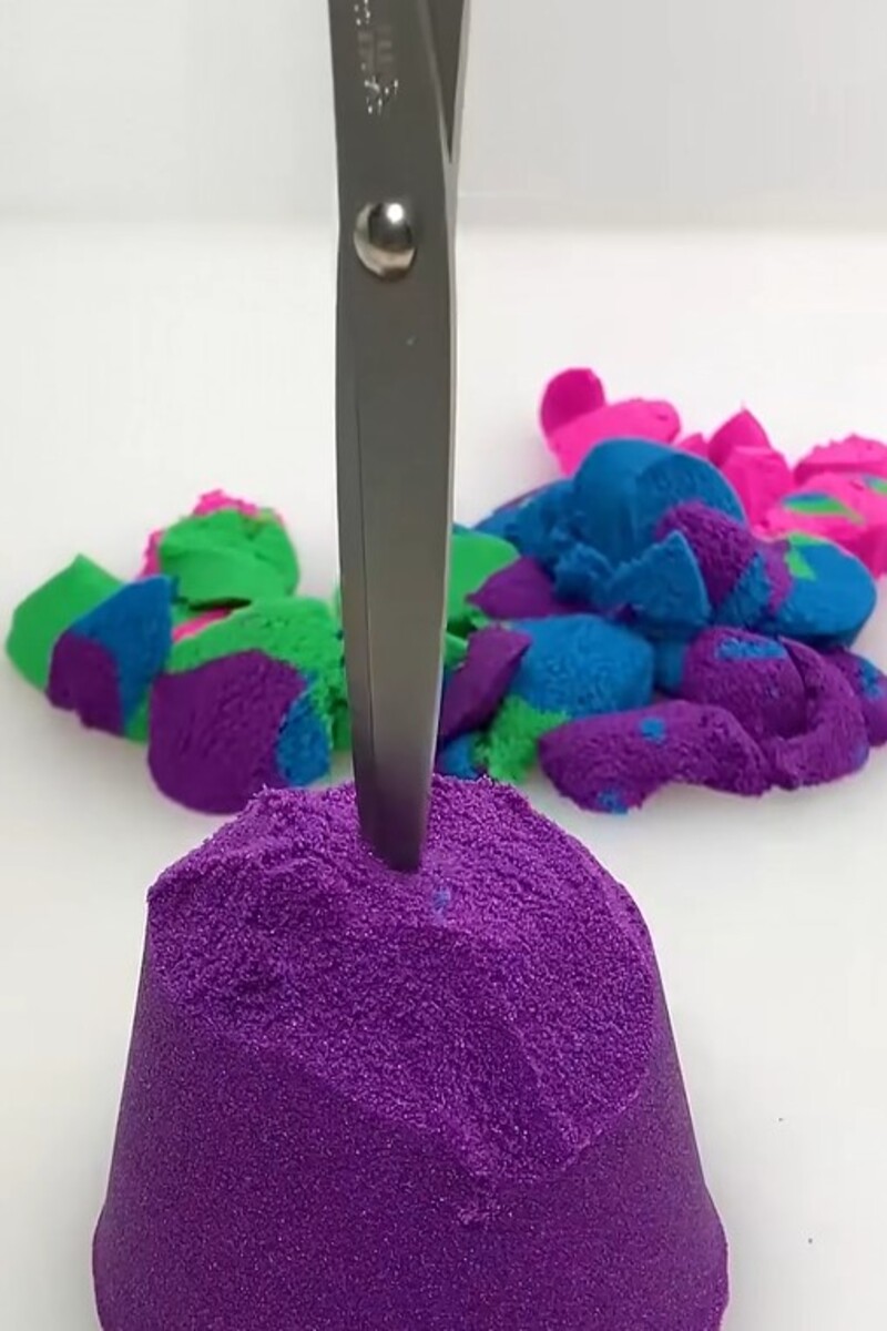 Scissors cutting purple kinetic sand