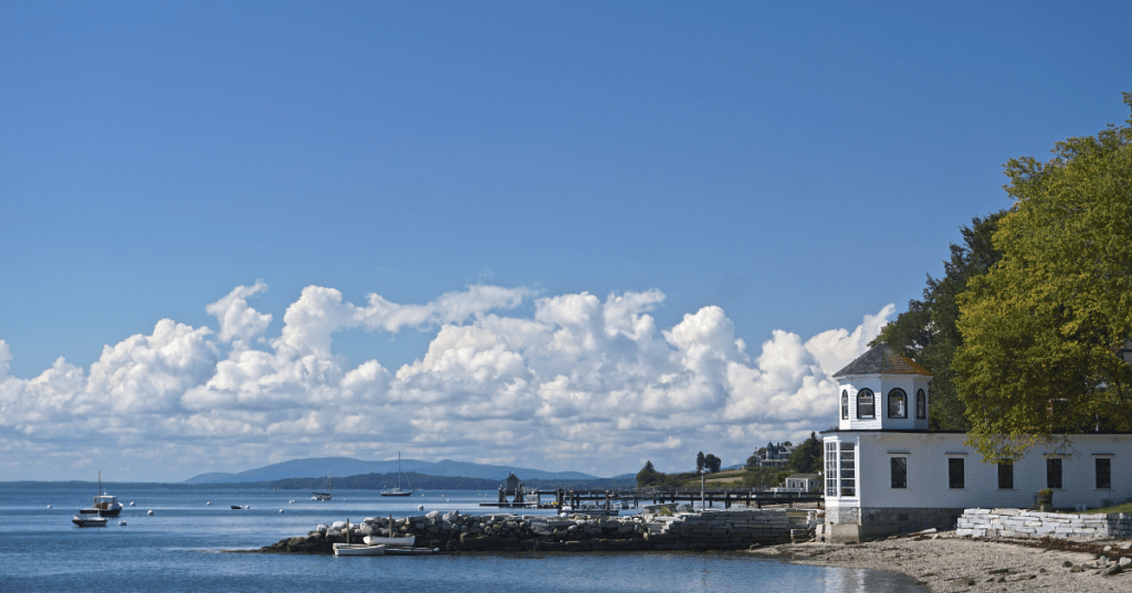 Beautiful white clouds in a blue sky over the harbor at Castine, with small boats in Penobscot Bay and mountains in the distance.