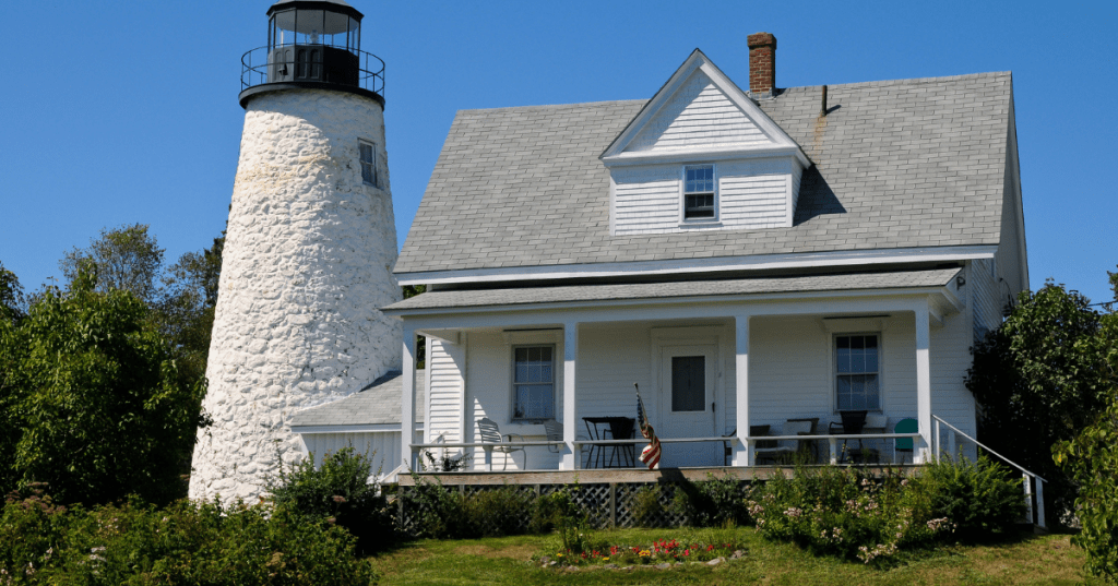 A white lighthouse structure next to a small white house.