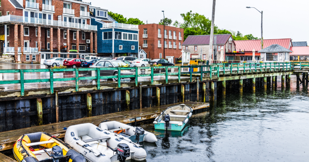 Empty wooden marina harbor in small village in Maine during rain with boats and parking lot