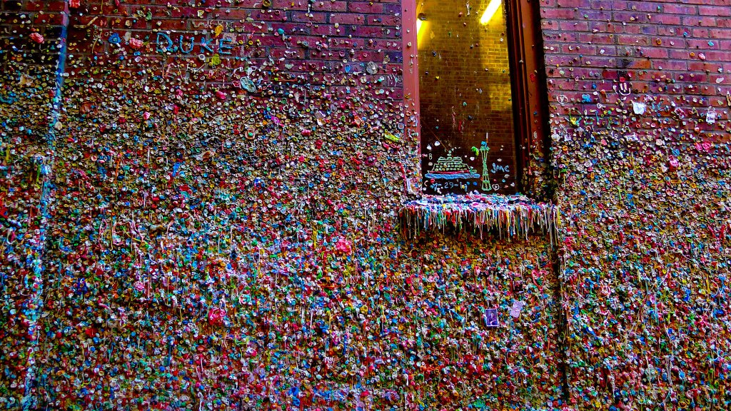 Colorful wall covered entirely in chewed gum, creating a textured, mosaic-like surface.