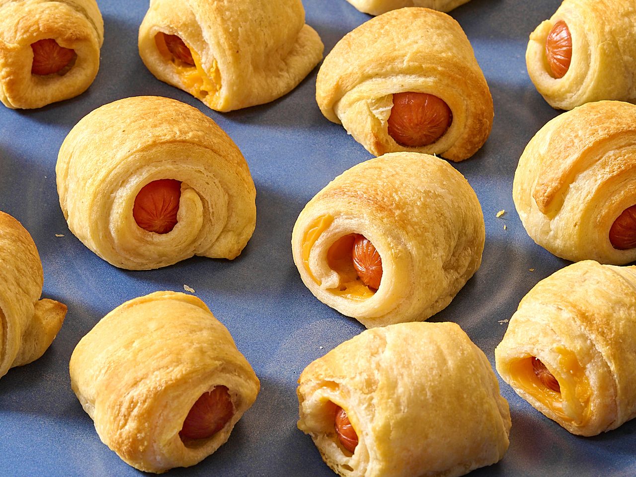 Several pigs in a blanket appetizers arranged on a blue surface