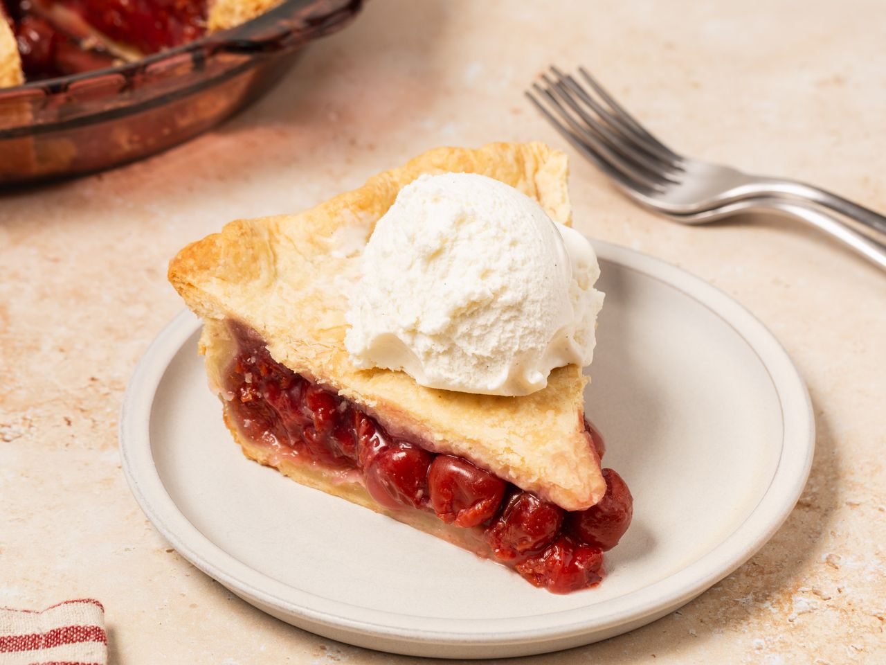 Slice of cherry pie with vanilla ice cream.