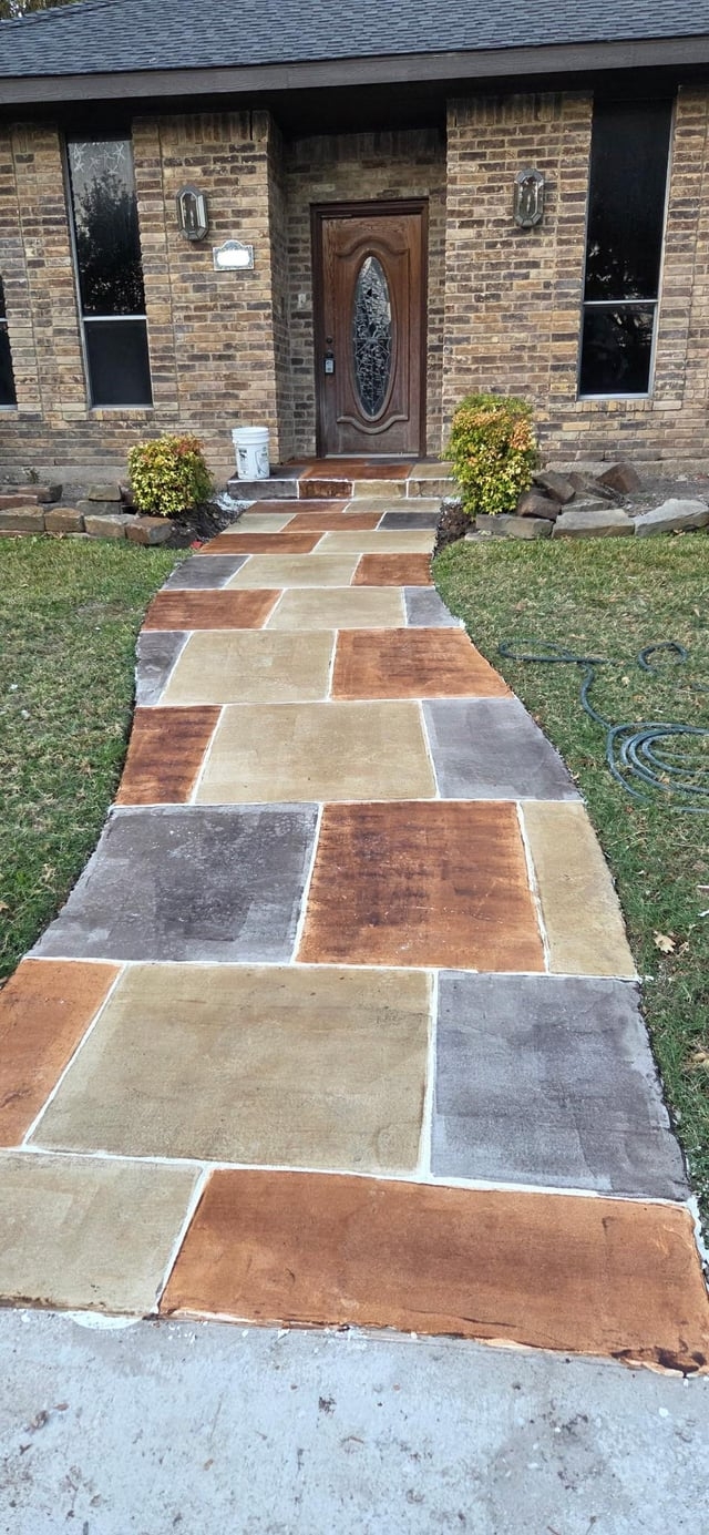 Curved walkway to a brick house with a wooden door, featuring large rectangular stone slabs in various shades