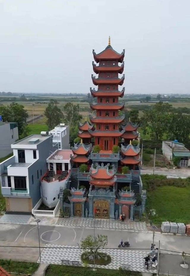 Pagoda with multiple tiers and ornate details, surrounded by modern buildings and countryside landscape