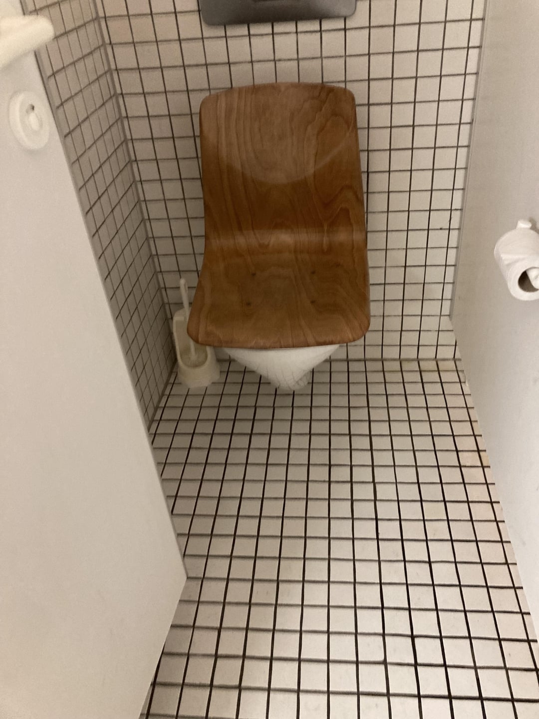 Innovative bathroom with a wooden chair base creatively fashioned as a toilet, set against a tiled wall and floor