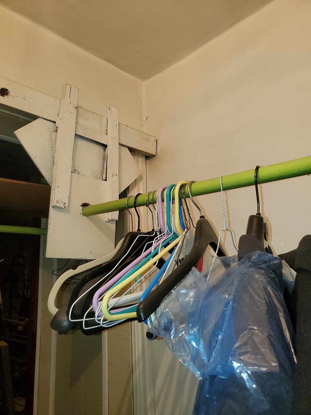 Empty hangers and a plastic-covered garment hanging on a rod in a closet corner