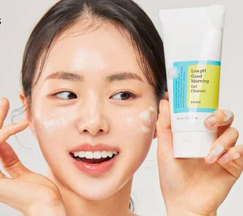 the model holding the bottle of cleanser