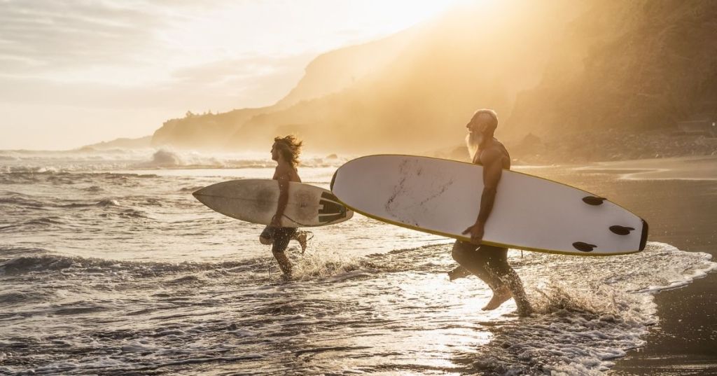 Two surfers heading into the ocean at dawn.